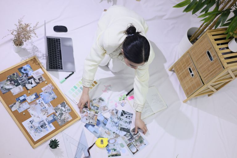 Overhead view of a person working in a creative space with a mood board, planner, and laptop.